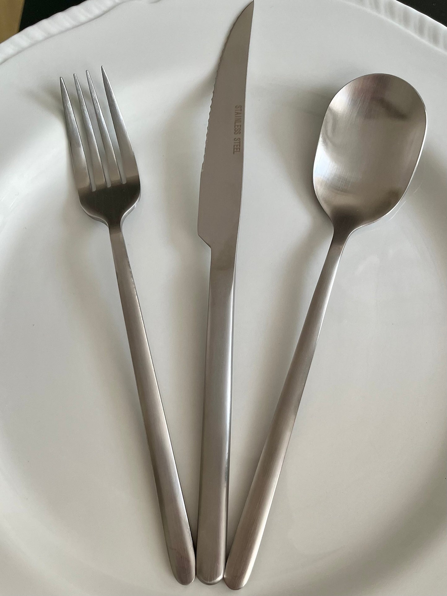 Avie 16-piece matte finish stainless steel cutlery set with forks, knives, spoons, and teaspoons neatly arranged on a modern dining table