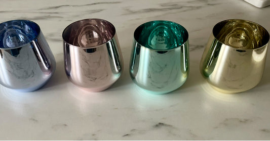 Set of 4 ribbed glass tumblers in assorted colors – green, blue, amber, and pink – displayed on a table, modern textured drinking glasses for water, juice, or cocktails.